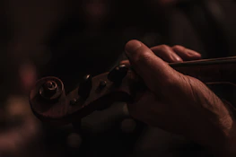 Hands smoothly drawing a bow across violin strings, capturing motion and sound.