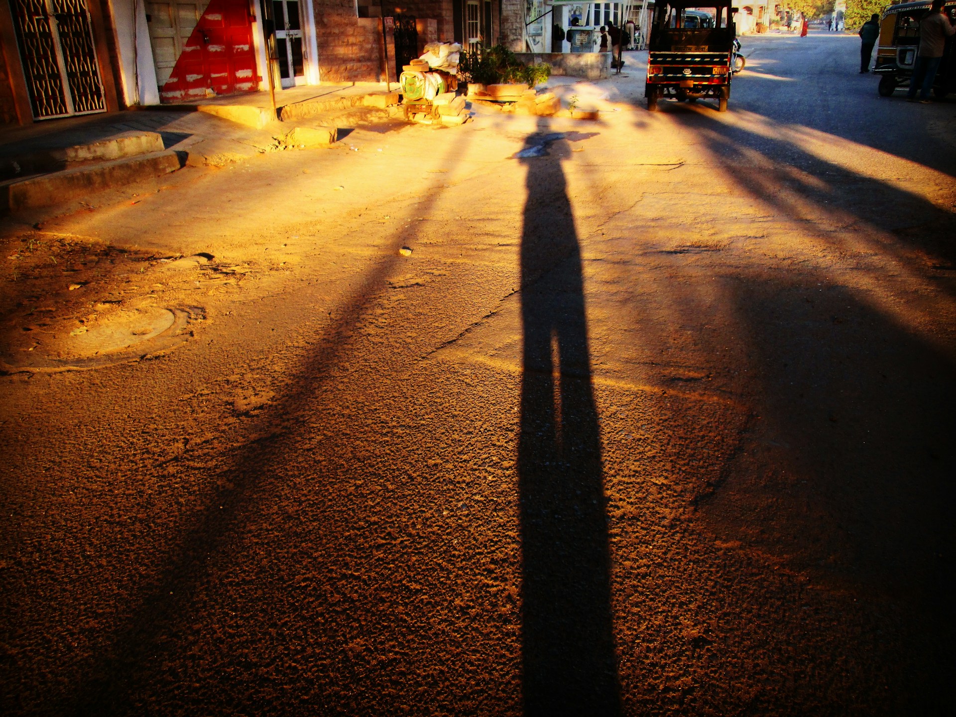 A rich, cinematic still capturing a dramatic Kolkata street scene at dusk, with intricate shadows and warm golden light highlighting everyday moments.