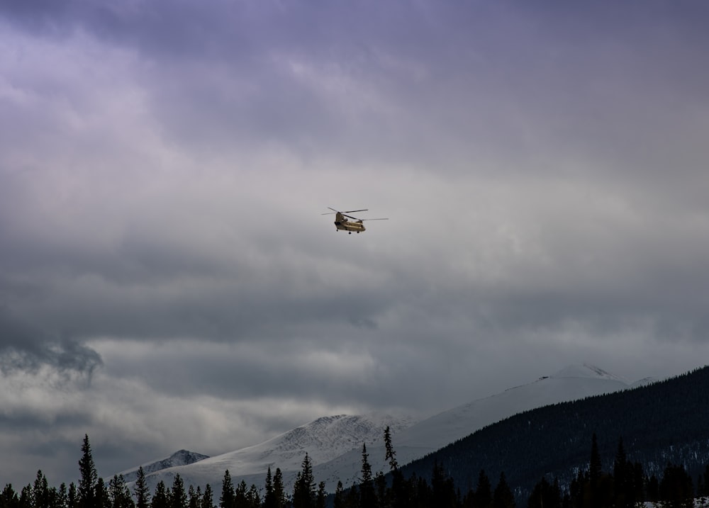 brown helicopter flying under cloudy sky