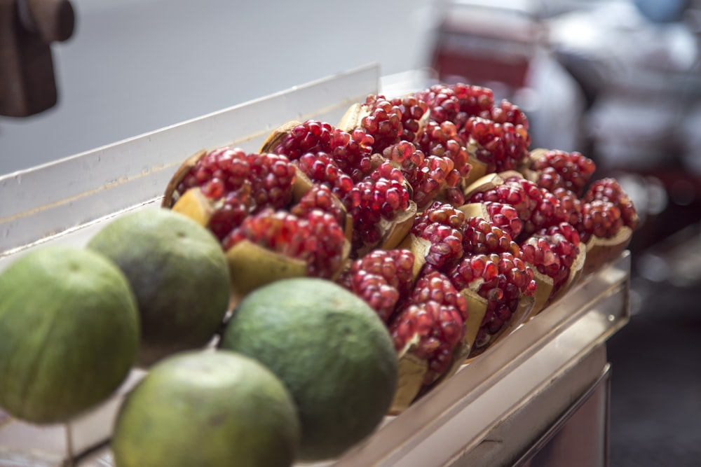 green and red fruits on white wooden shelf