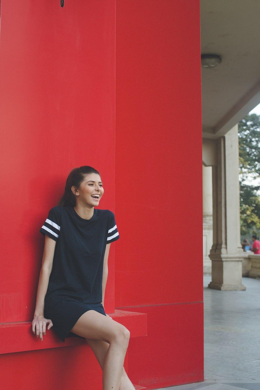 A happy woman sitting on a red ledge.