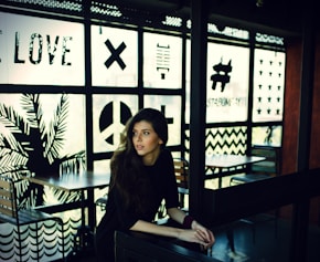 woman in black quarter-sleeved top leaning on black desk