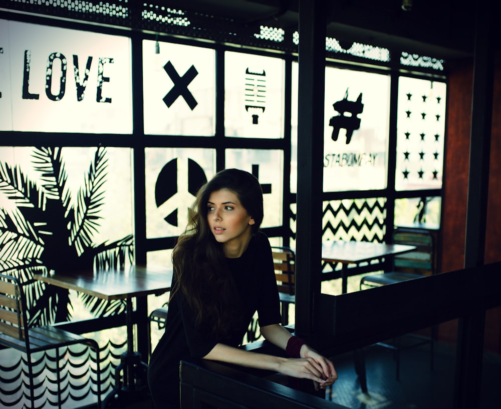 woman in black quarter-sleeved top leaning on black desk