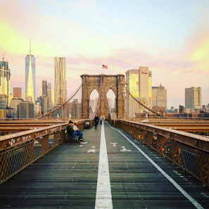 Close-up portrait of a tourist with the Brooklyn Bridge softly blurred in the background during sunset