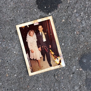 A gentle hand holding a weathered photograph of a couple smiling in younger days.