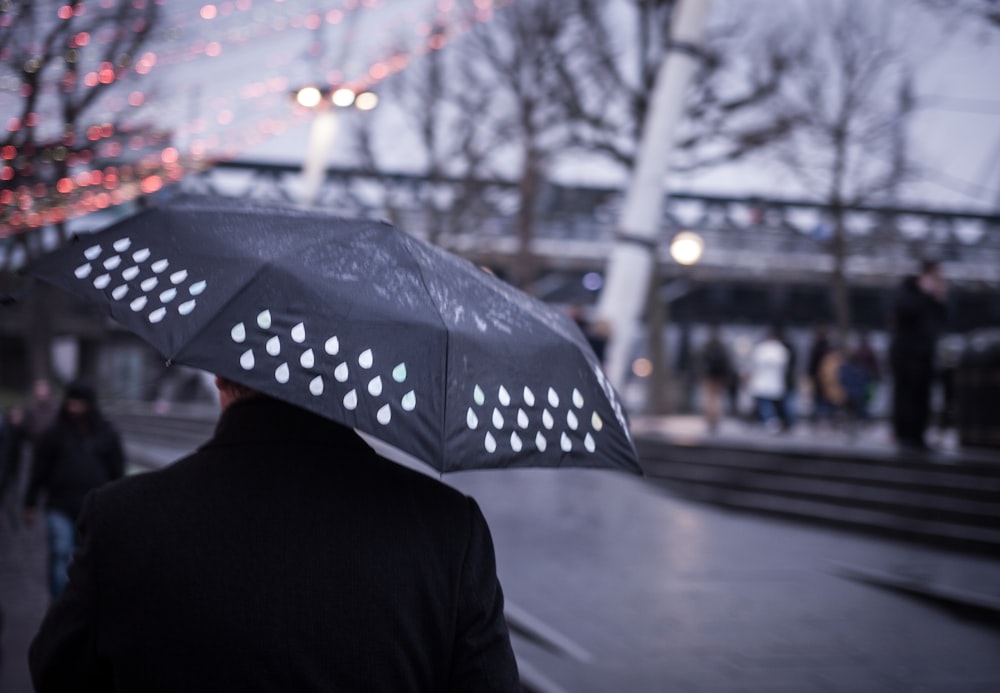 pessoa segurando guarda-chuva preto