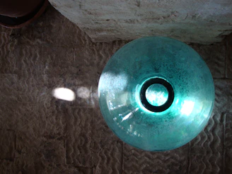 Close-up of a textured stoneware bowl with a glossy turquoise glaze catching the light.