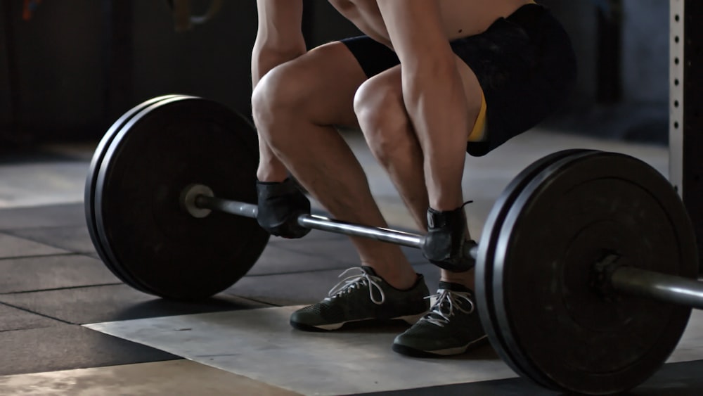 A person bending over to lift a barbell with two 45 pound plates on each side.