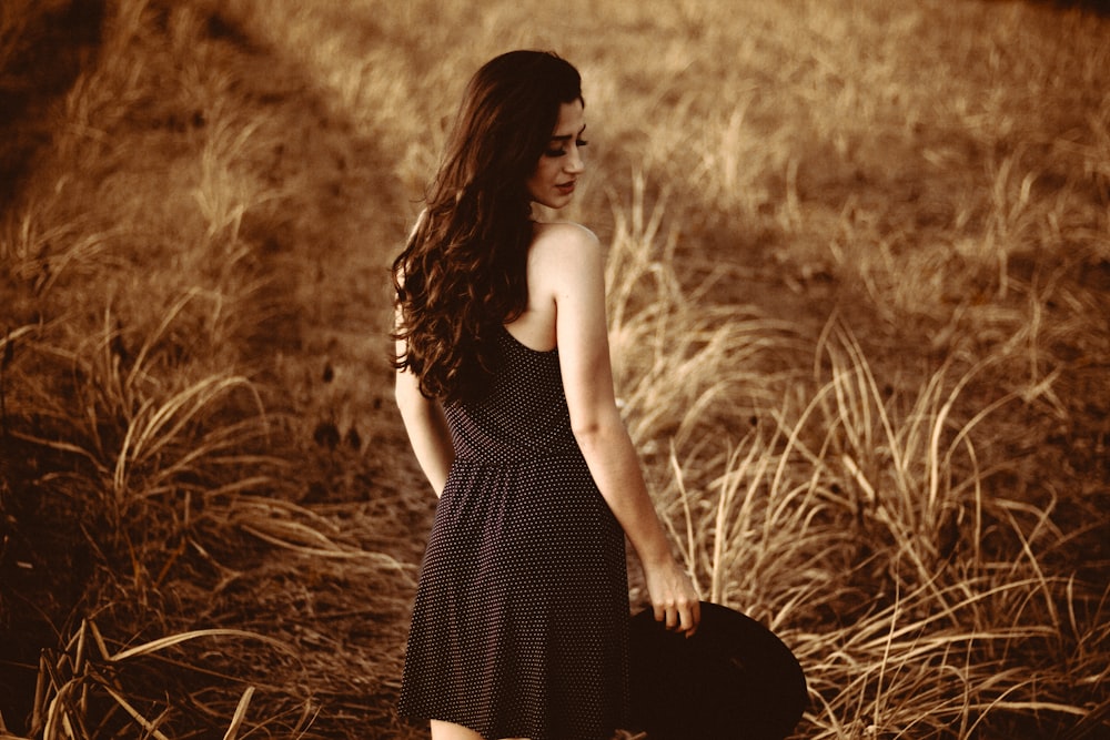 standing woman holding hat at the field during day