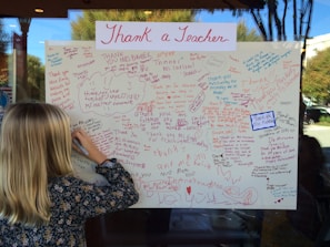 A smiling child holding a handmade thank-you card in a bright classroom