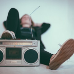 woman laying on bed near gray radio