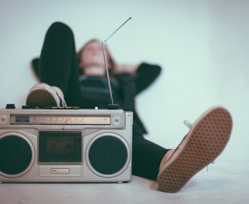 woman laying on bed near gray radio