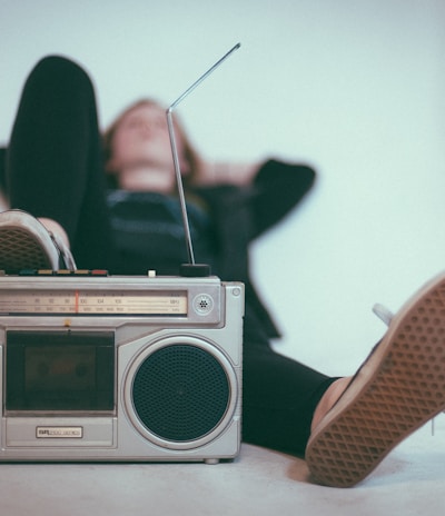 woman laying on bed near gray radio