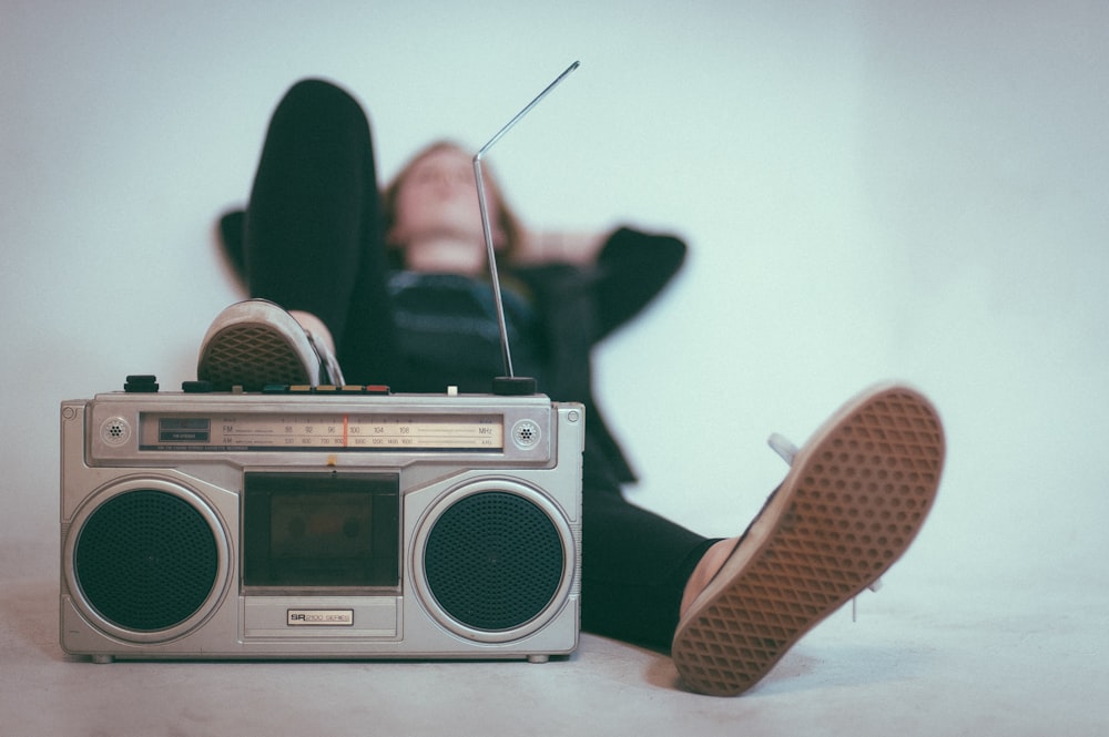 woman laying on bed near gray radio