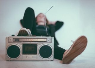 woman laying on bed near gray radio