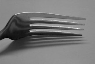 Close-up of a finely crafted tuning fork resting on a clean white surface.
