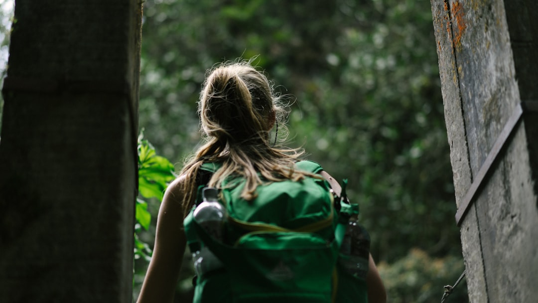 person wearing green backpack, Woman walks through wood doors