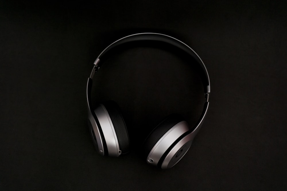 Silberne Kopfhörer auf schwarzer Oberfläche
