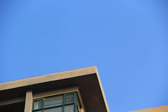 A modern architectural building with clean lines and large glass windows under a clear blue sky.