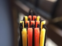 Close-up view of colorful bristles of a toothbrush, featuring red, yellow, and black colors arranged in alternating rows.