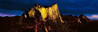 Dramatic mountain runner at dawn on a rugged trail in Sierra Blanca, with dark skies and orange-golden light highlighting the terrain.