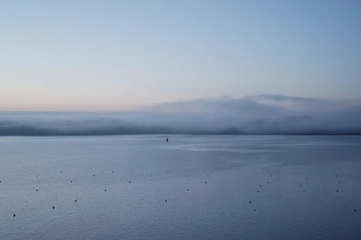 A serene turquoise ocean at dawn with soft mist rising above the water, evoking calm and spiritual awakening.