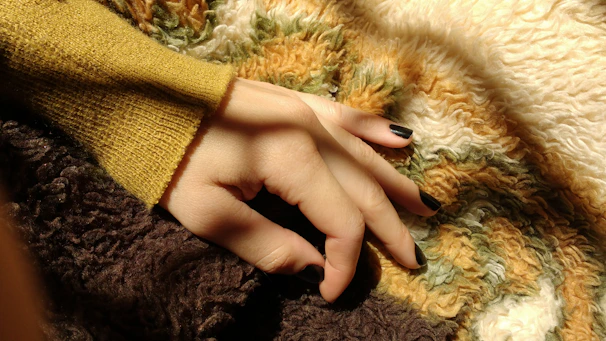 A set of freshly painted nails in bright colors, resting on a cozy blanket.