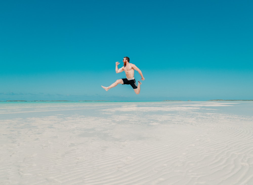fotografia time lapse dell'uomo che salta in riva al mare