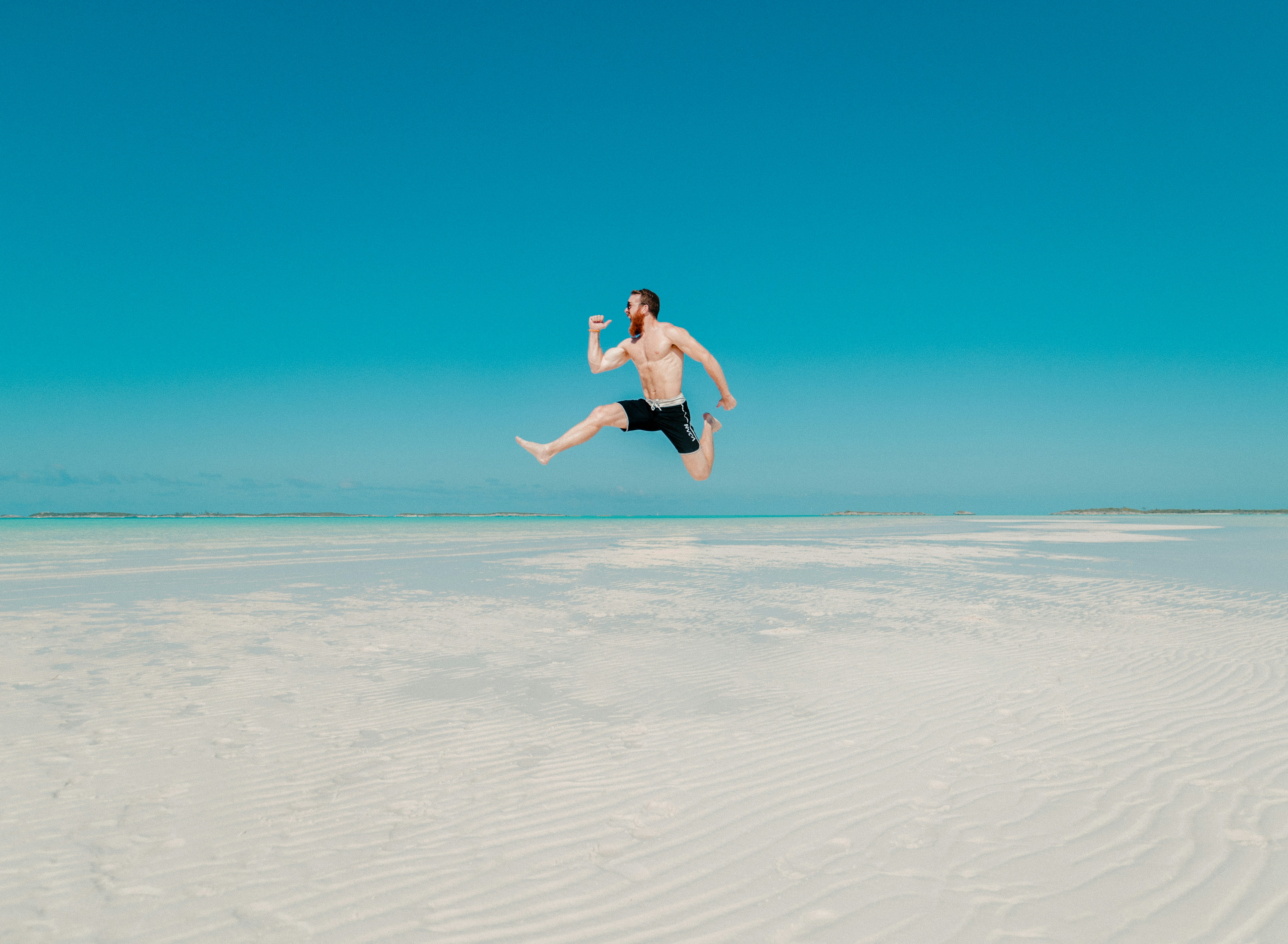 time lapse photography of man jumping at seashore
