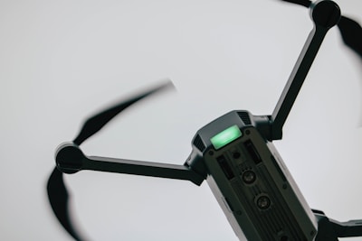 A close-up view of a drone with spinning rotors, capturing its metallic structure and a green indicator light on its body.