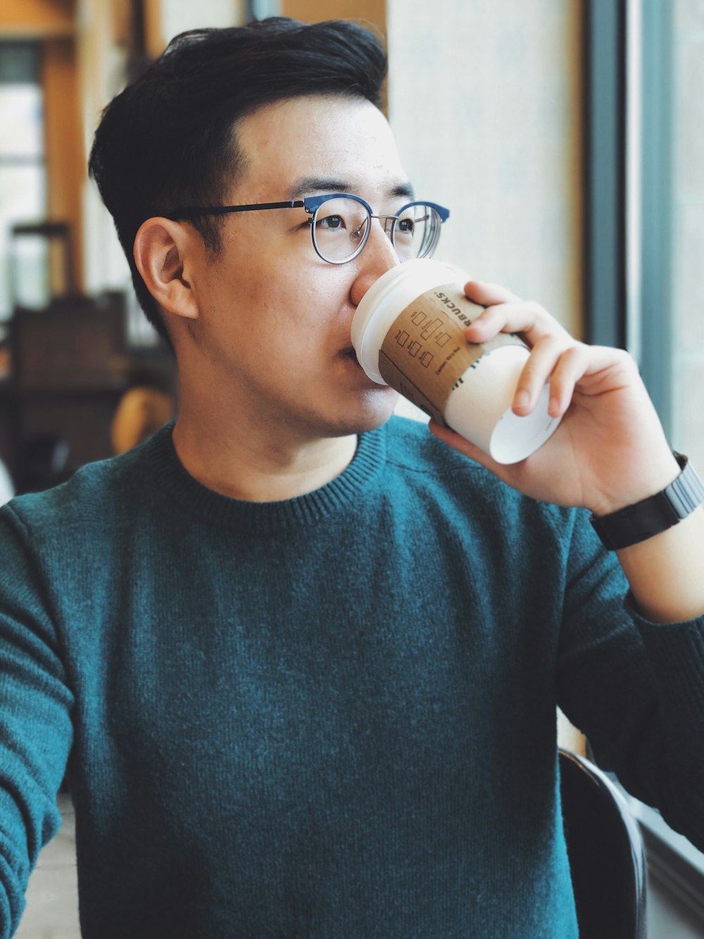 hombre sosteniendo un vaso desechable de Starbucks