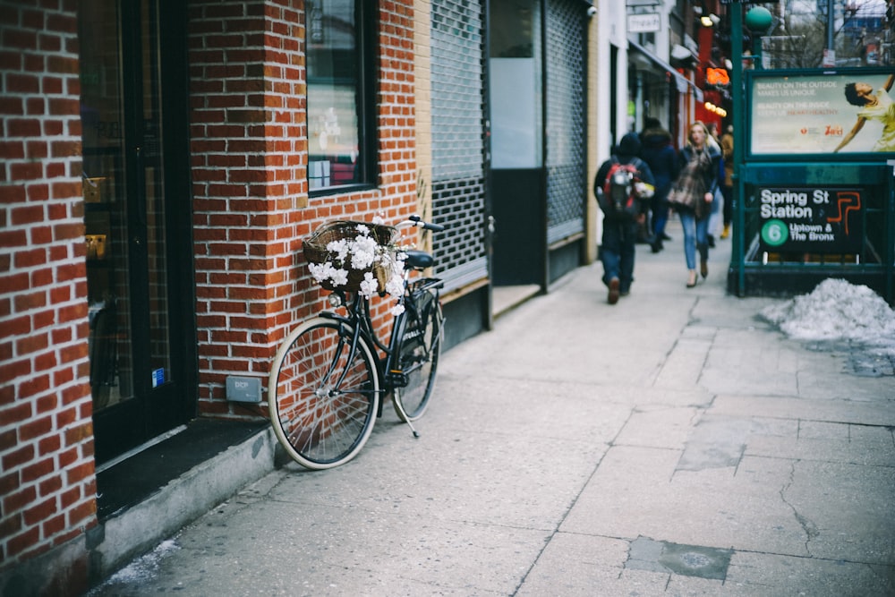 Bicicletta nera della città parcheggiata accanto al muro di mattoni di cemento marrone