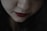 A close-up of a woman applying lipstick in a softly lit room.