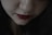 A close-up of a woman applying lipstick in a softly lit room.