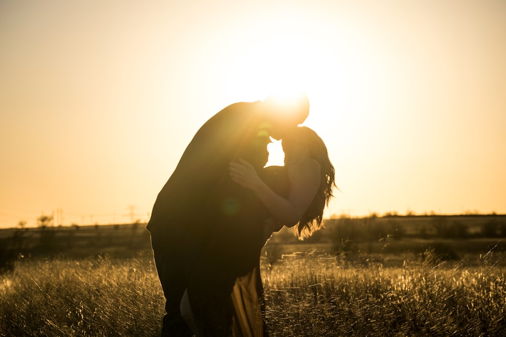 man and woman kissing on grass field during day time