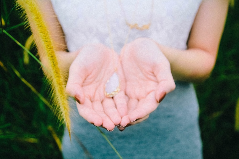 white and gold-colored pendant on person's hand