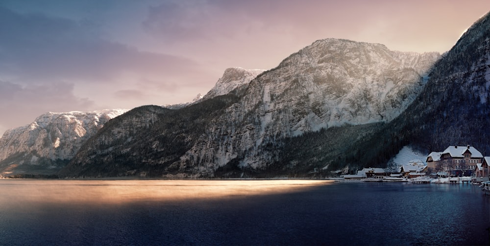 brown and white house beside body of water covered with shadow of mountain