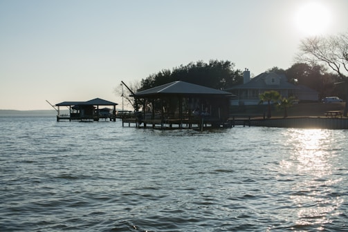 A charming lakeside home with a wooden dock and calm water reflecting the sunset.
