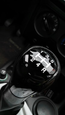 Close-up of a driving school car's dual pedal system in a modern workshop setting.