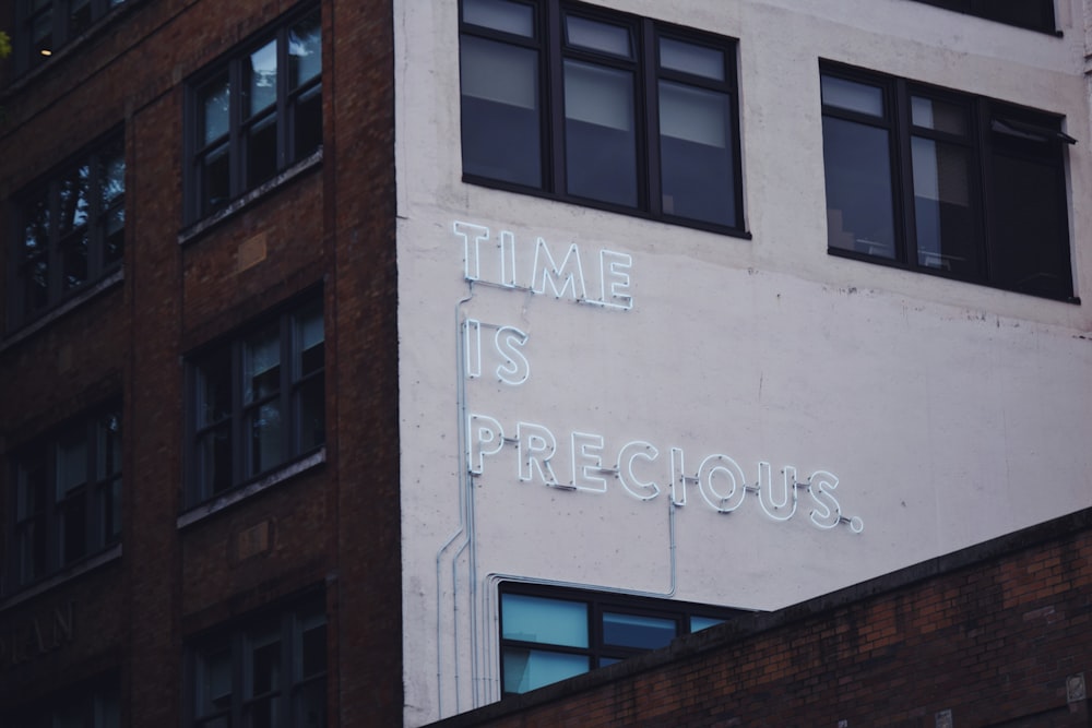 white Time Is Precious signage building at daytime