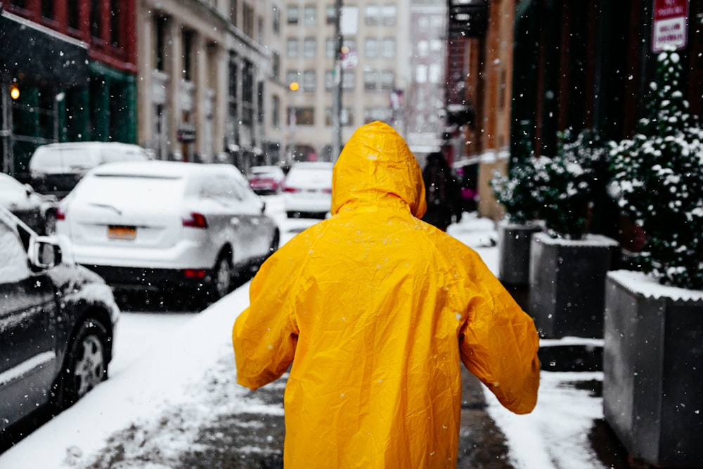 person wearing yellow raincoat walking in the street