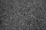 Close-up of freshly paved asphalt with a smooth, dark finish under bright sunlight.