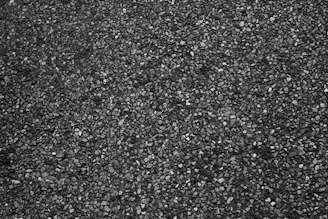 Close-up of fresh asphalt mixture being poured from a truck onto a road surface.