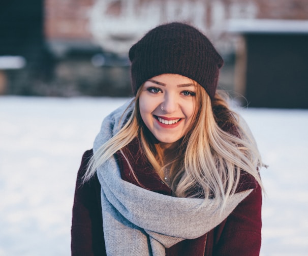 smiling woman wearing brown scarf and maroon coat on snow field