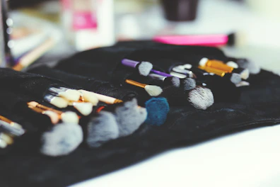 A sleek set of makeup brushes resting on a soft fabric background.