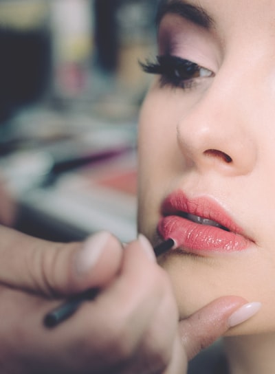 woman getting lips applied with lipstick