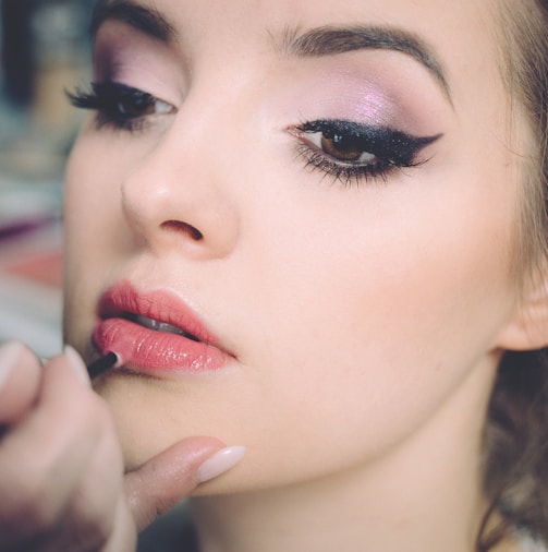 woman getting lips applied with lipstick