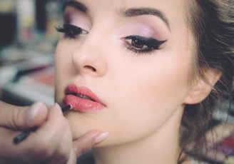 woman getting lips applied with lipstick