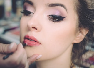 woman getting lips applied with lipstick