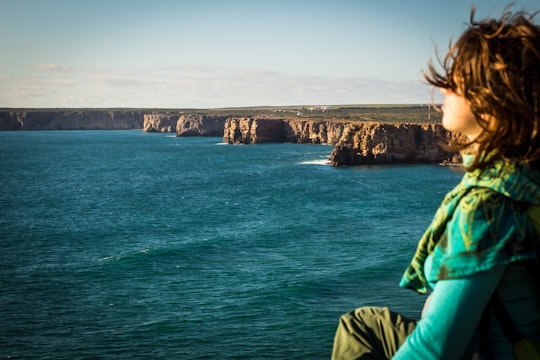 woman sitting at the seashore in Fortaleza de Sagres Portugal